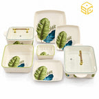 Glamour square dinnerware with green and teal-blue leaves, green-rimmed bowls and clear-lidded serving dishes is displayed against a white background.