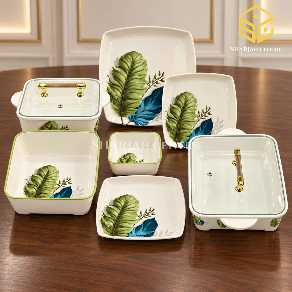 Glamour botanical plates, bowls and covered serving dishes with gold-tone handles are arranged on a wooden table.