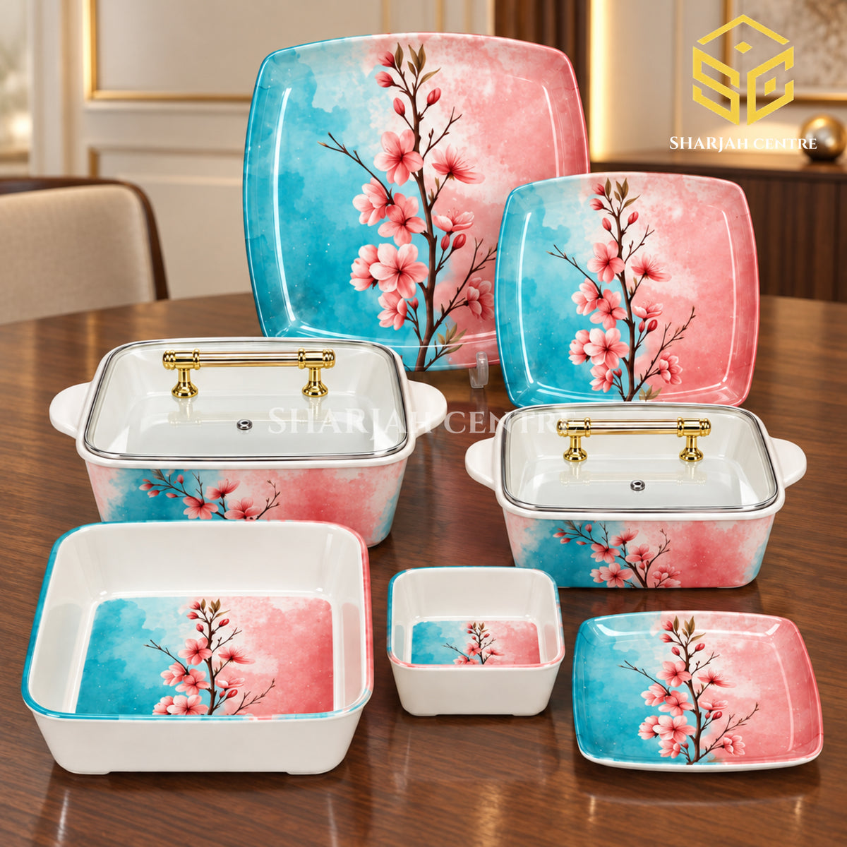 Glamour turquoise and pink blossom plates, bowls and covered serving dishes with gold-tone handles are arranged on a wooden table.