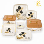 Glamour ivory square dinnerware features black flowers, golden-brown leaves and amber lids with gold-tone handles against a white background.