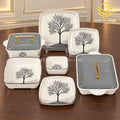 Glamour Black Tree plates, bowls and covered serving dishes with gold-tone handles are displayed on a wooden table.