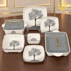 Glamour Black Tree plates, bowls and covered serving dishes with gold-tone handles are displayed on a wooden table.