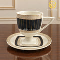 ivory black gold cup and saucer, gold lattice pattern, black panel design, pedestal tea cup, luxury wooden table setting, Sharjah Centre Multan