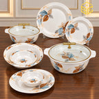 The Modern leaf-pattern dinner set is arranged on a wooden table with clear lids and gold-tone handles on the serving bowls.